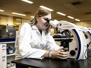 Student laboratoriumtechniek achter microscoop